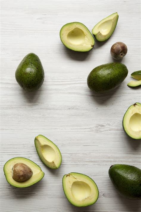 Whole And Chopped Avocados On White Wooden Background Overhead View