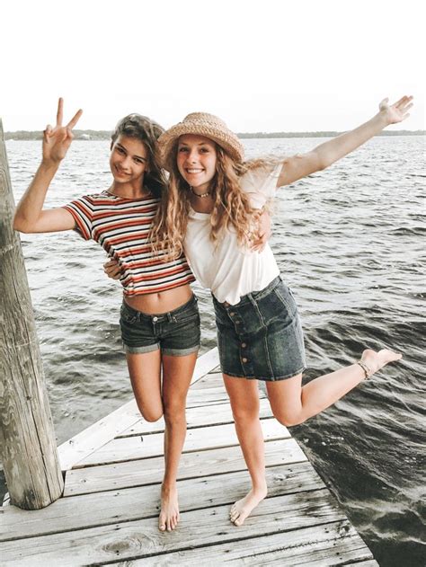 Two Babe Women Standing On A Dock With Their Arms In The Air