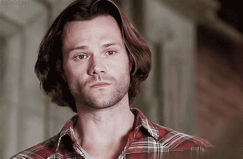 A Man With Long Hair Wearing A Red And White Checkered Shirt Looking At The Camera