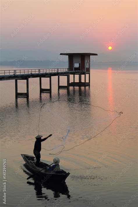 Silhouette Of Fishermen Using Nets To Catch Fish At The Bangpra Lake