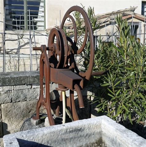 Ancienne pompe manuelle à manivelle sur fontaine en pierre avec double