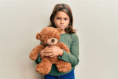 Little Beautiful Girl Hugging Teddy Bear Skeptic And Nervous Frowning Upset Because Of Problem