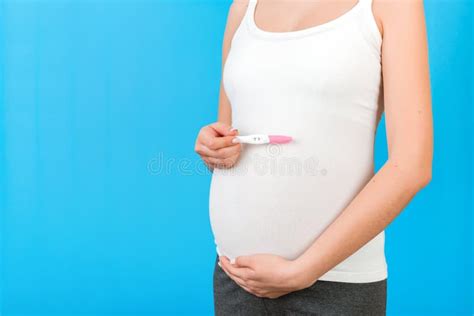 Close Up Of Pregnant Woman In Home Clothing Holding Positive Pregnancy
