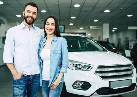 Feliz Pareja Joven Elige Y Compra Un Auto Nuevo Para La Familia En El Concesionario Foto Premium