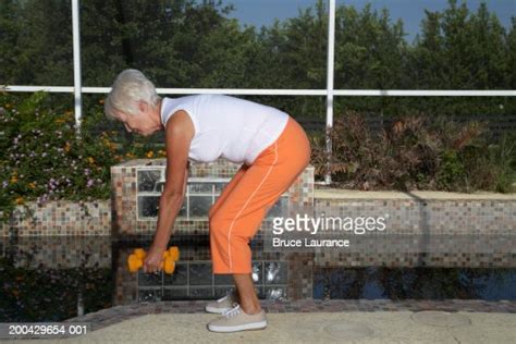 Senior Woman Bending Over And Lifting Weights High Res Stock Photo