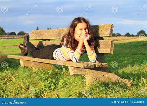 Una Bambina Sdraiata Sulla Panchina Del Sole Fotografia Stock Immagine Di Osservare Quindici