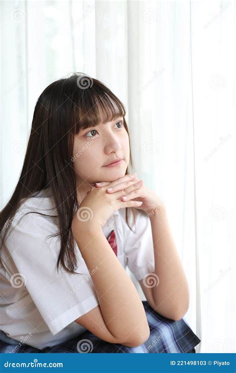 Portrait Japanese School Girl Uniform Sitting And Look At Camera In White Tone Bed Room Stock