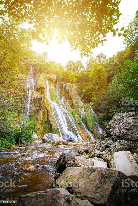 Majestic Waterfall In French Forest With Streaming Sunlight Stock Photo