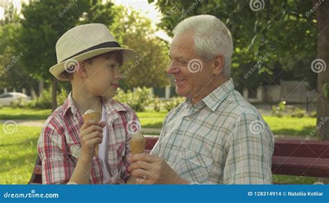 Senior Man And His Grandson Eat Ice Cream On The Bench Stock Photo