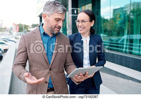 Confident businessman discussing online data with his colleague on the move. Young confident ...