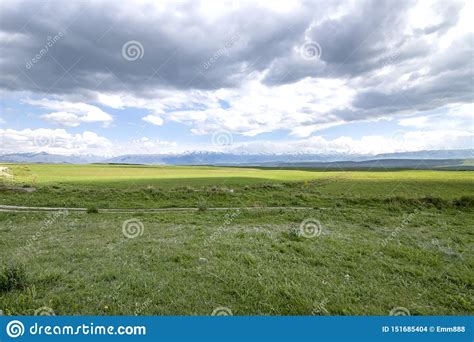 Country Road Among Green Fields And Hills Against The Backdrop Of