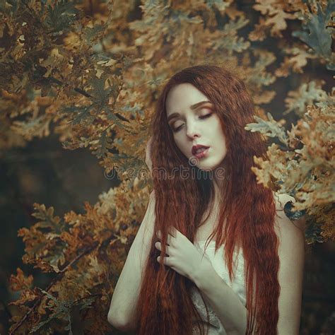 portret van een mooie jonge sensuele vrouw met zeer lang rood haar in de herfst eiken bladeren