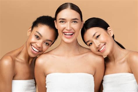 Three Ladies Wrapped In Bath Towels Posing On Beige Background Stock