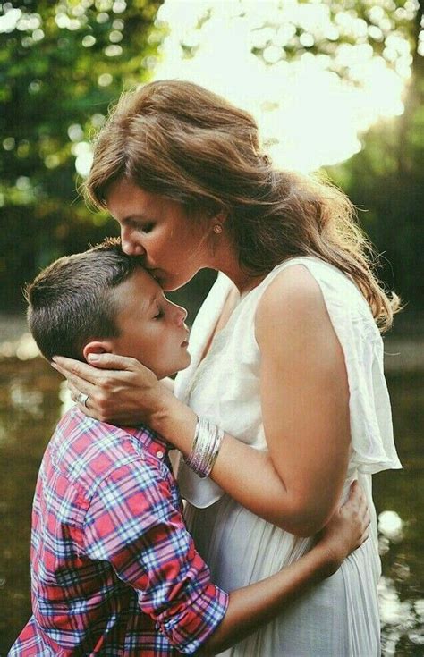 A Woman Kissing A Boy In Front Of Water