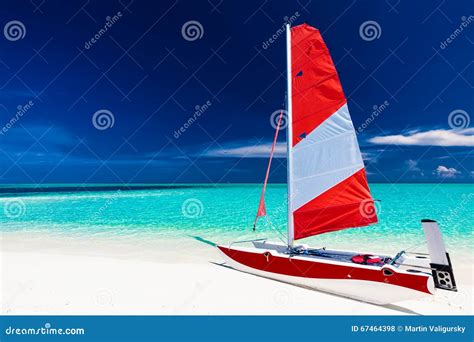 Sailing Boat With Red Sail On A Beach Of Deserted Tropical Islan Stock