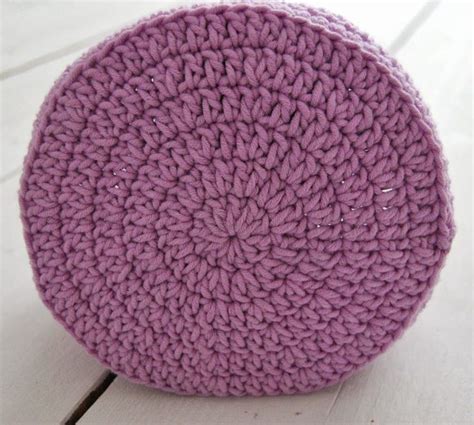A Purple Crocheted Round Object Sitting On Top Of A White Wooden Floor