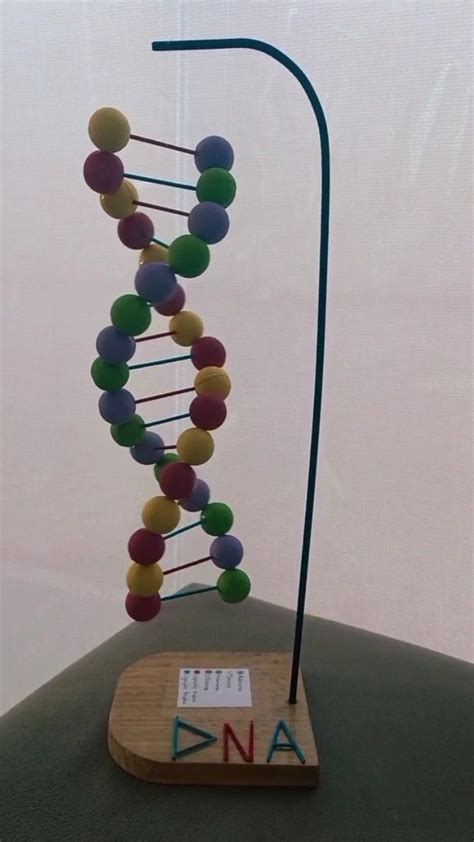 A Wooden Stand Holding A Model Of A Structure With Colorful Balls On It S Sides