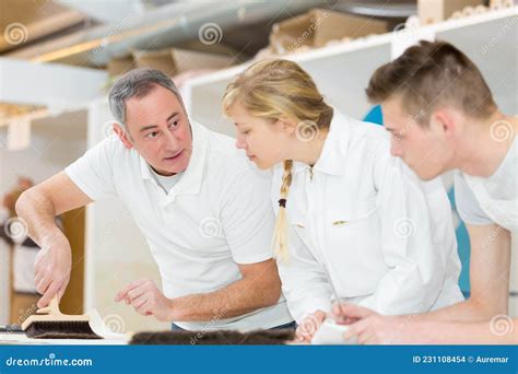 Supervisor Showing Apprentices How To Use Wallpaper Brush Stock Photo