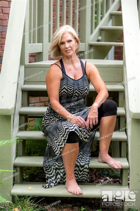 A Portrait Of A 56 Year Old Blond Woman Sitting On Wooden Porch Steps
