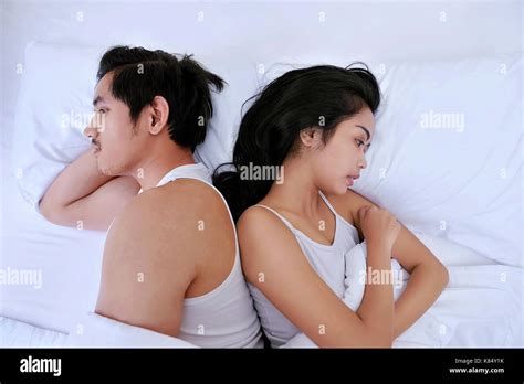 Upset Asian Couple Having Problems With Lying Side By Side In Bed