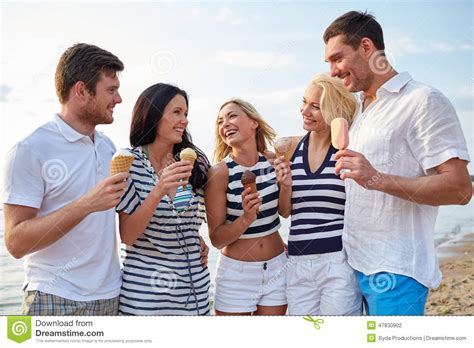 Friends Eating Ice Cream And Talking On Beach Stock Photo
