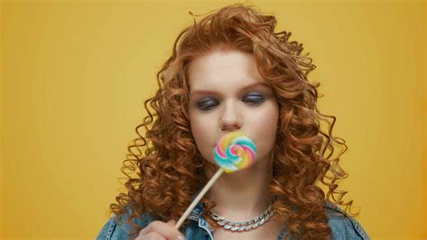 Closeup Attractive Woman Holding Colorful Lollipop In Studio Portrait Of Smiling Girl Covering