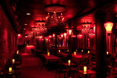 A Dimly Lit Restaurant With Red Lighting And Chandeliers Hanging From