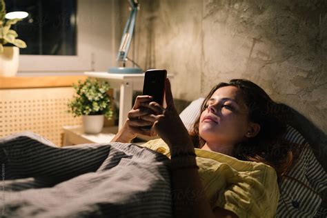 Young Woman Using Her Phone In Bed By Stocksy Contributor Mihajlo