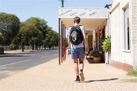 Teenage Boy Walking Down A Deserted Street In A Small Town