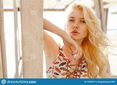 Blonde With Curly Hair Blue Eyes Big Lips Supported On A Wooden