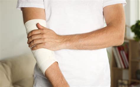 Man With Arm Wrapped In Medical Bandage Indoors Closeup Stock Image