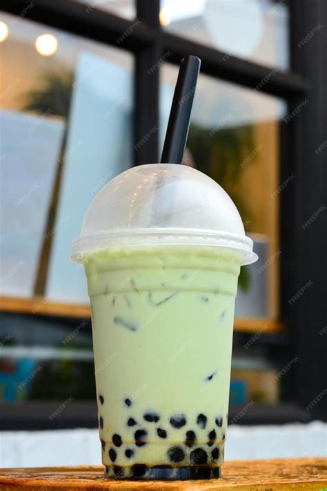 premium photo glass of milk bubble matcha green tea with tapioca pearls on blurred cafe