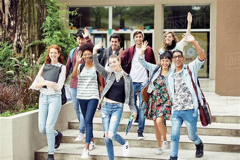 College students waving while walking on campus - Stock Photo - Dissolve