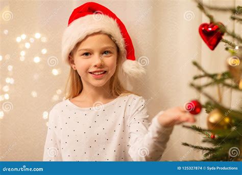 Happy Girl In Santa Hat Decorating Christmas Tree Stock Photo Image