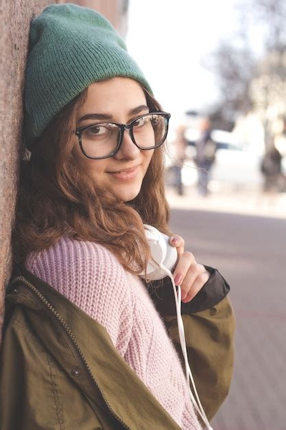 Premium Photo Cute Hipster Girl In Glasses And Hat Smiling Stands On A City Street Fashion