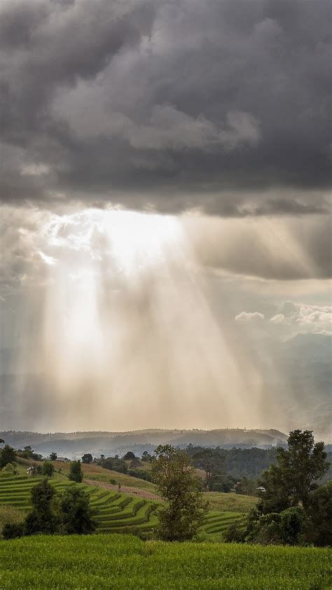 Storm clouds with rain and sunbeam over the mountain, Thailand ...