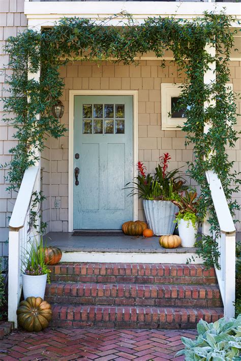 The Front Porch Is Decorated With Pumpkins And Greenery