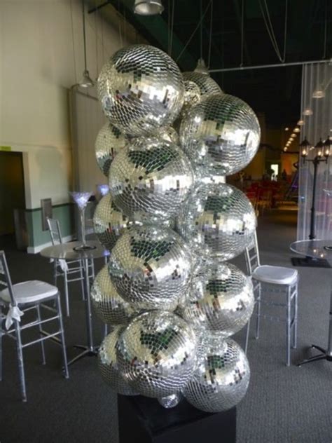 A Large Stack Of Shiny Disco Balls Sitting On Top Of A Black Pedestal