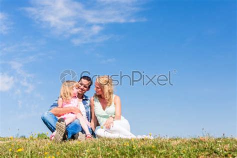 Girl On Dads Lap Sitting On Meadow Or In Field Stock Photo