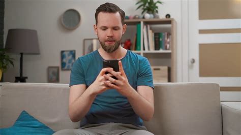 Portrait Of Young Caucasian Man Using Modern Mobile Smartphone Sitting