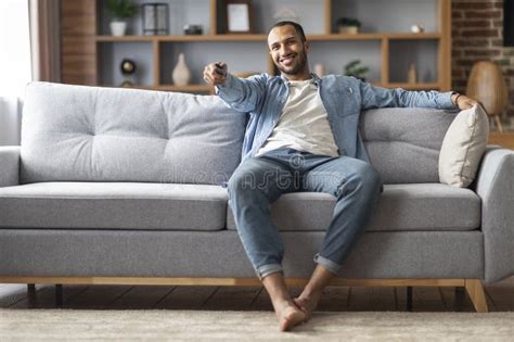 Home Relax Handsome Black Man Sitting On Couch And Switching Tv