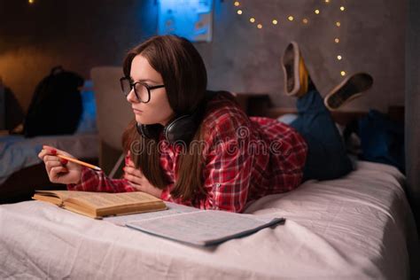 College Student Doing Homework In Bed At Dormitory Young Woman