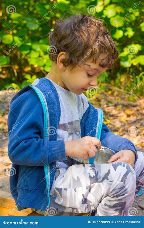 un chico blanco y chiquito come papilla de un bol en un picnic al aire libre imagen de archivo