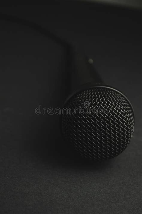 Vertical Closeup Shot Of A Black Microphone On A Black Background Stock