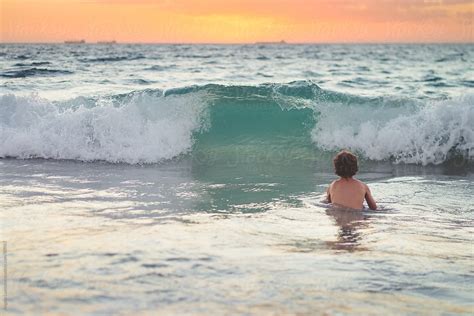 Boy Swimming At The Beach At Sunset Del Colaborador De Stocksy