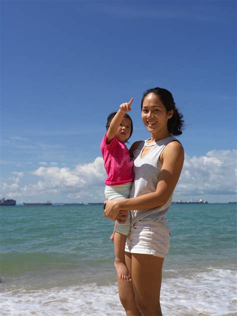 Young Asian Chinese Mother Carrying Her Daughter By The Sea Side Stock