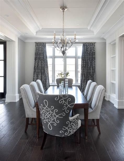 The solid grey stained oak table has a curvaceous base. Gray dining room features a tray ceiling accented with a ...