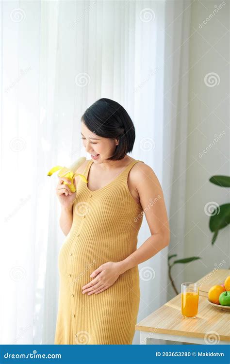 Pregnant Woman On Living Room With Healthy Fruit Juice And Eating