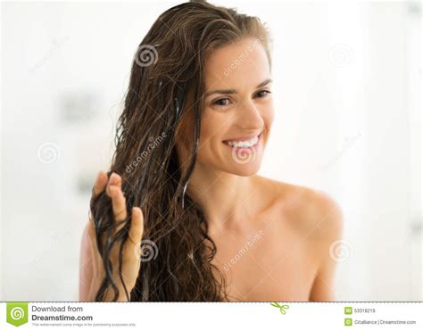 Happy Young Woman Applying Hair Mask In Bathroom Stock