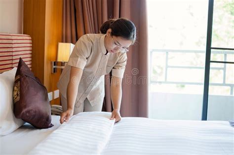 The Hotel Maid Cleans And Makes The Bed In The Hotel Room Stock Image